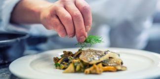 Chef in hotel restaurant kitchen cooking a fish cuisine