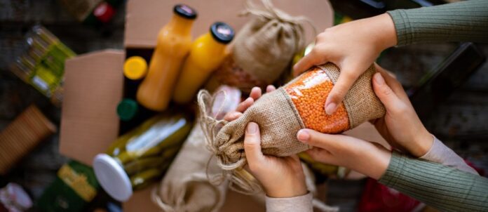 Box full of foods and drinks with mulitple hands holding a bag of rice