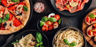 full table of italian meals on plates pizza, pasta, ravioli, and carpaccio