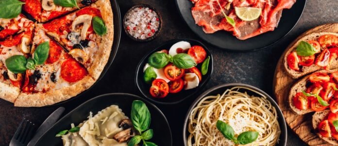 full table of italian meals on plates pizza, pasta, ravioli, and carpaccio