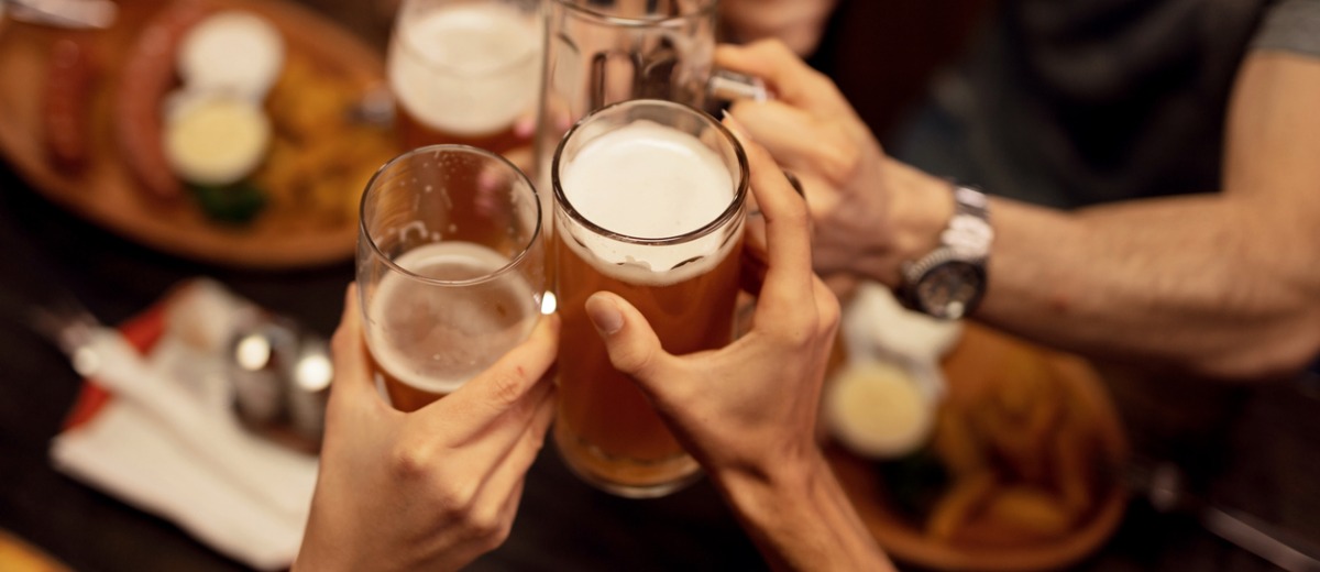 Close up of friends toasting with beer and having fun in a pub