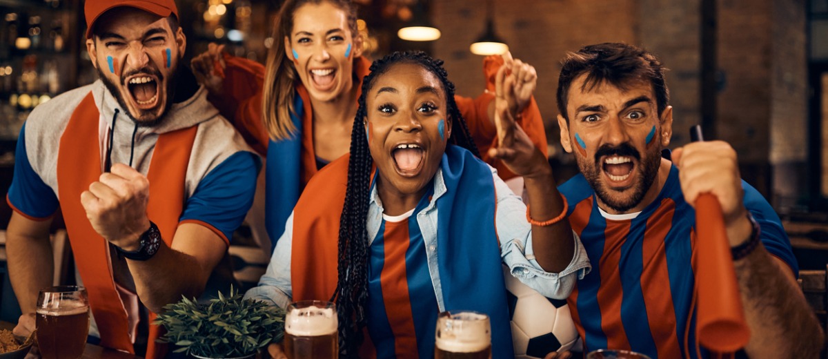 Passionate sports fans cheering while watching a game in pub