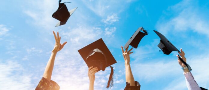 Four graduates throwing graduation hats in the air