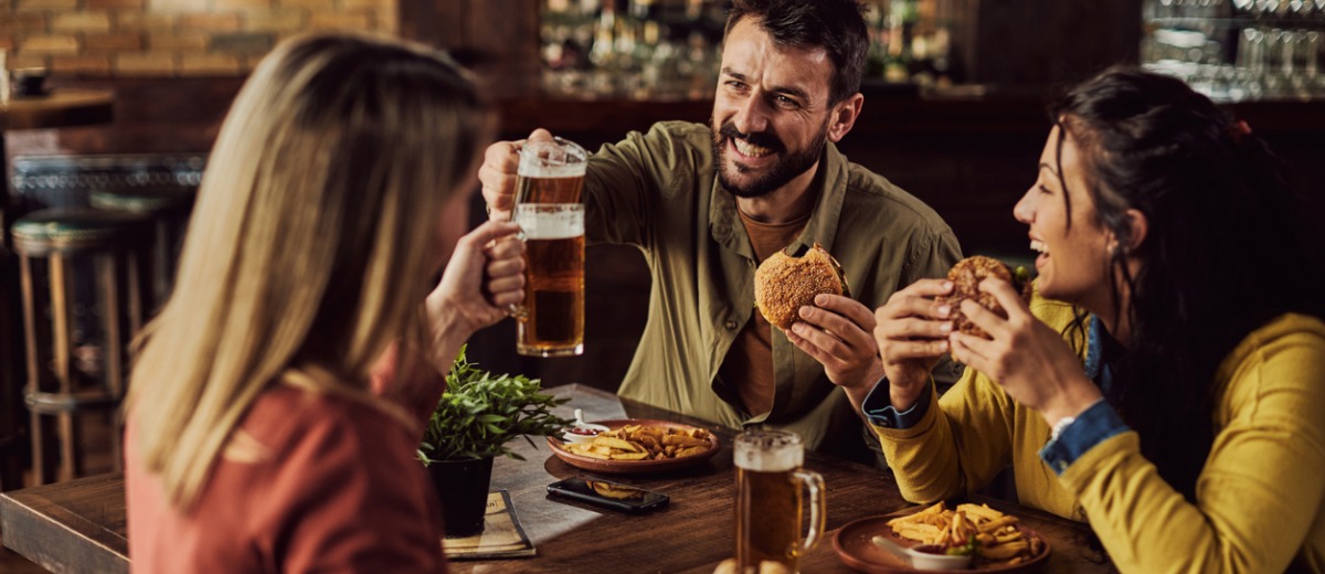 Young happy man toasting with friends while having lunch in a pub.