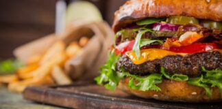 Hamburger on cutting board with french fries beside it