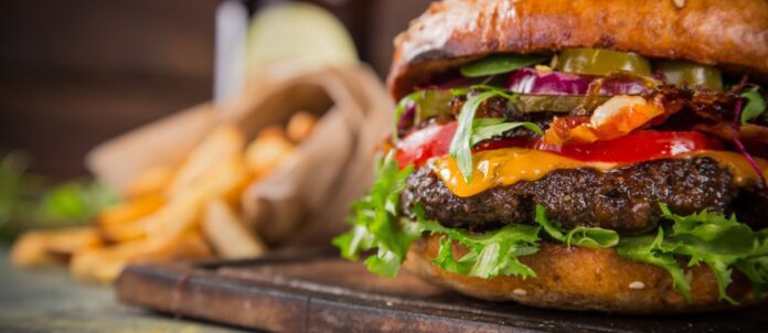 Hamburger on cutting board with french fries beside it