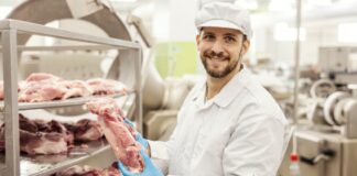 Meat factory worker is holding piece of raw meat