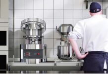 Chef in kitchen with mixer appliances in background