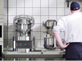 Chef in kitchen with mixer appliances in background