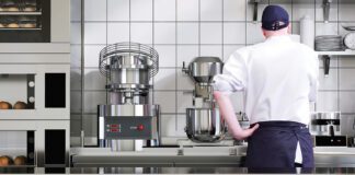 Chef in kitchen with mixer appliances in background