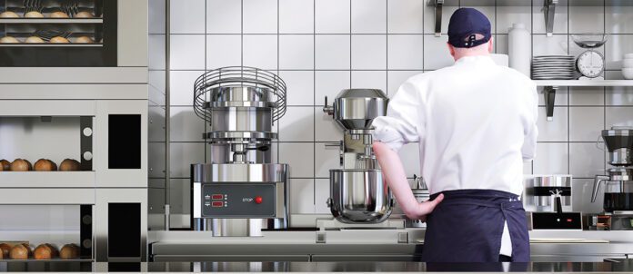 Chef in kitchen with mixer appliances in background