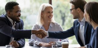 Businesspeople shake hands get acquainted greeting at team meeting in office.