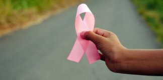 Man holding breast cancer awareness ribbon near road