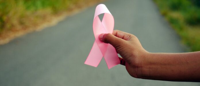 Man holding breast cancer awareness ribbon near road