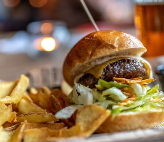 Burger with french fries on the side and a craft beer