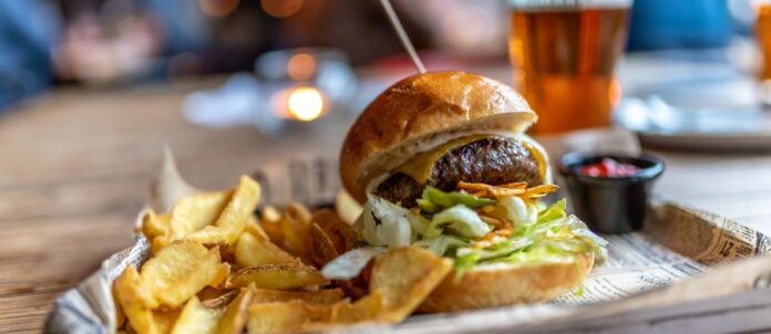 Burger with french fries on the side and a craft beer