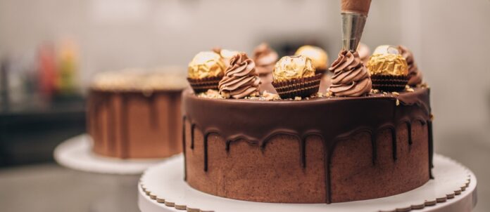 Confectioner decorating chocolate cake close-up