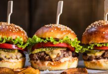 Cheeseburgers on wooden board and table in dark and moody light