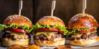 Cheeseburgers on wooden board and table in dark and moody light