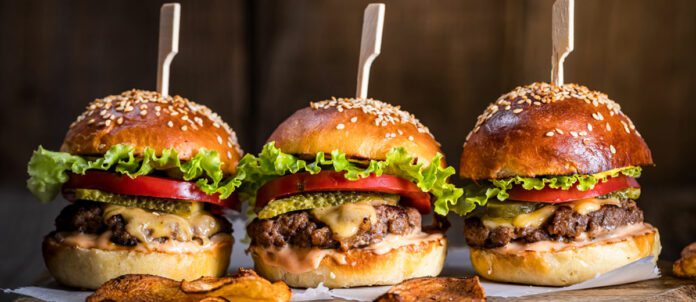 Cheeseburgers on wooden board and table in dark and moody light