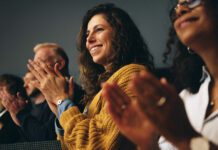 Businesspeople sitting in audience and applauding at conference