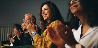 Businesspeople sitting in audience and applauding at conference