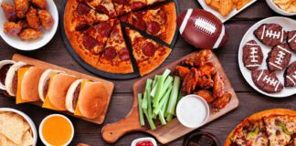 Football superbowl party platter with Pizza, hamburgers, wings, snacks and sides on wooden table