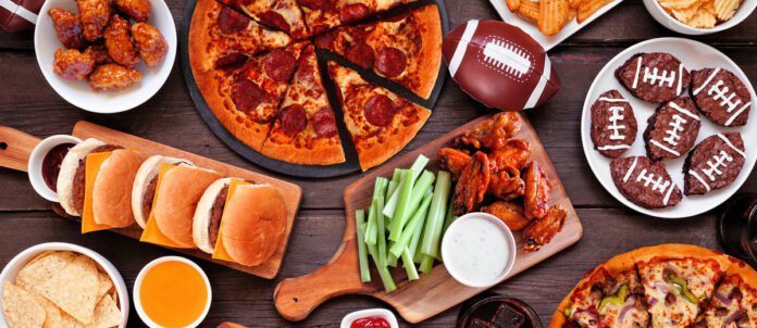 Football superbowl party platter with Pizza, hamburgers, wings, snacks and sides on wooden table