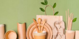 Craft paper utensils, takeaway paper containers and cups, bamboo cutlery, paper drinking straws on green background