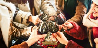 Young people socializing drinking and eating food sitting outside at winery bar table