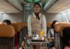 Flight attendant pushing the cart on aisle for serving food and drink to passengers in airplane cabin