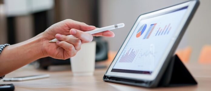 Close up corporate employee pointing at tablet while reading report and analytics