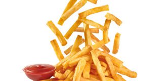 French Fries dropping down onto a plate with ketchup on the side