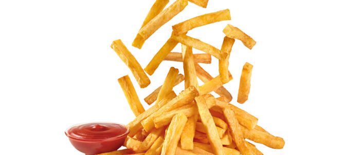 French Fries dropping down onto a plate with ketchup on the side