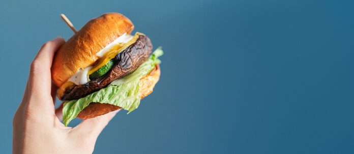 Person's hand hold a vegetarian hamburger