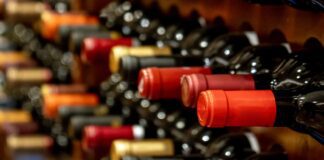 Bottles of black red wine lined up and stacked on wooden wine rack shelves