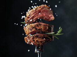 steak being cooked on fork with salt being sprinkled down
