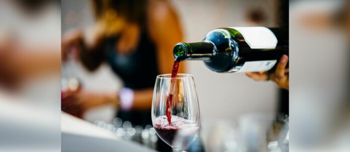 Man pouring red wine to wine glass.