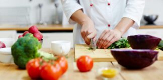 Chef of restaurant cooking fresh vegetable salad from green and red vegetables