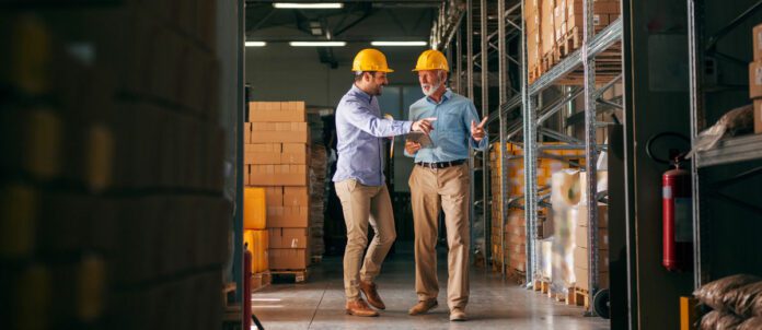 Factory workers walking and pointing at boxes to move.