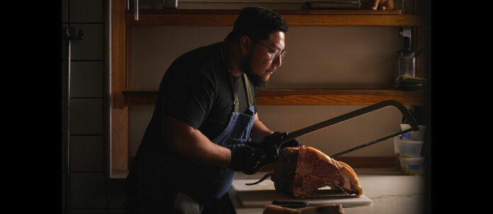 Head chef at Savio Volpe, Jorge Sora cutting beef in kitchen