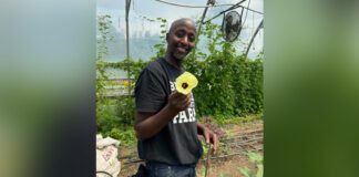 Chef advocate Bashir Munye holding the flower of an okra plant | Photo credit: Rosanna Caira