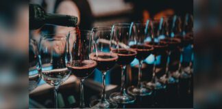 Sommelier pouring red wine into long-stemmed wineglasses