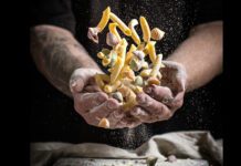 Chef hold an assorted group of pasta covered in flour