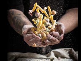 Chef hold an assorted group of pasta covered in flour