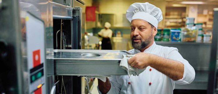 Chef taking food out of industrial oven