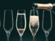 Row of Champagne glasses with hand pouring bottle