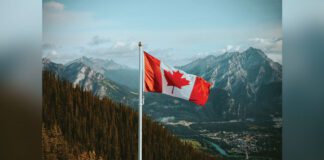 Canadian flag waving in breeze with mountain in background