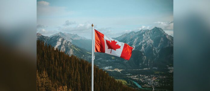 Canadian flag waving in breeze with mountain in background
