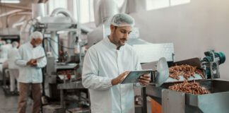 supervisor evaluating quality of food in food plant while holding tablet